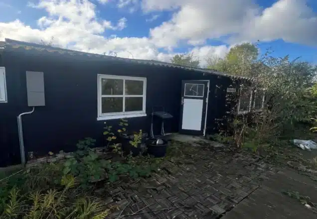 Find Kolonihave haveområde med blå bygning og havegang.