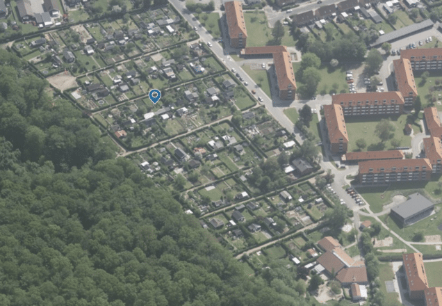 Aerial view af kolonihaver i Svendborg med grønne områder og boligblokke.